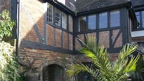 A traditional half-timbered house with a brick archway entrance, a conservatory with glass doors, and a variety of plants. - Village House Hotel - Inn (Worthing)