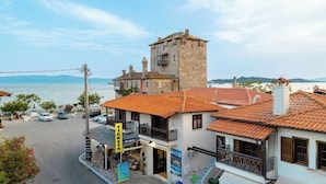 Un pueblo costero con una torre destacada, un edificio con balcón y un cartel que dice 'Tickets'.