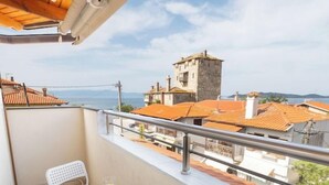 Un balcón con una mesa y dos sillas, con vistas a un pueblo con edificios tradicionales y una torre.