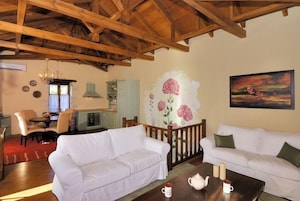 A cozy living room with white sofas, a wooden coffee table, and a dining area with a table and chairs.