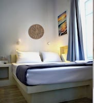 Un dormitorio moderno con una cama, mesitas de noche, un aplique de pared y un ventanal con cortinas.