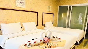 Habitació d'hotel amb dos llits, un capçal de llit de fusta, un mur floral i una porta corredissa.