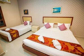 Camera d'albergo con due letti, ognuno dotato di poggiatesta, comodino e un quadro appeso al muro.