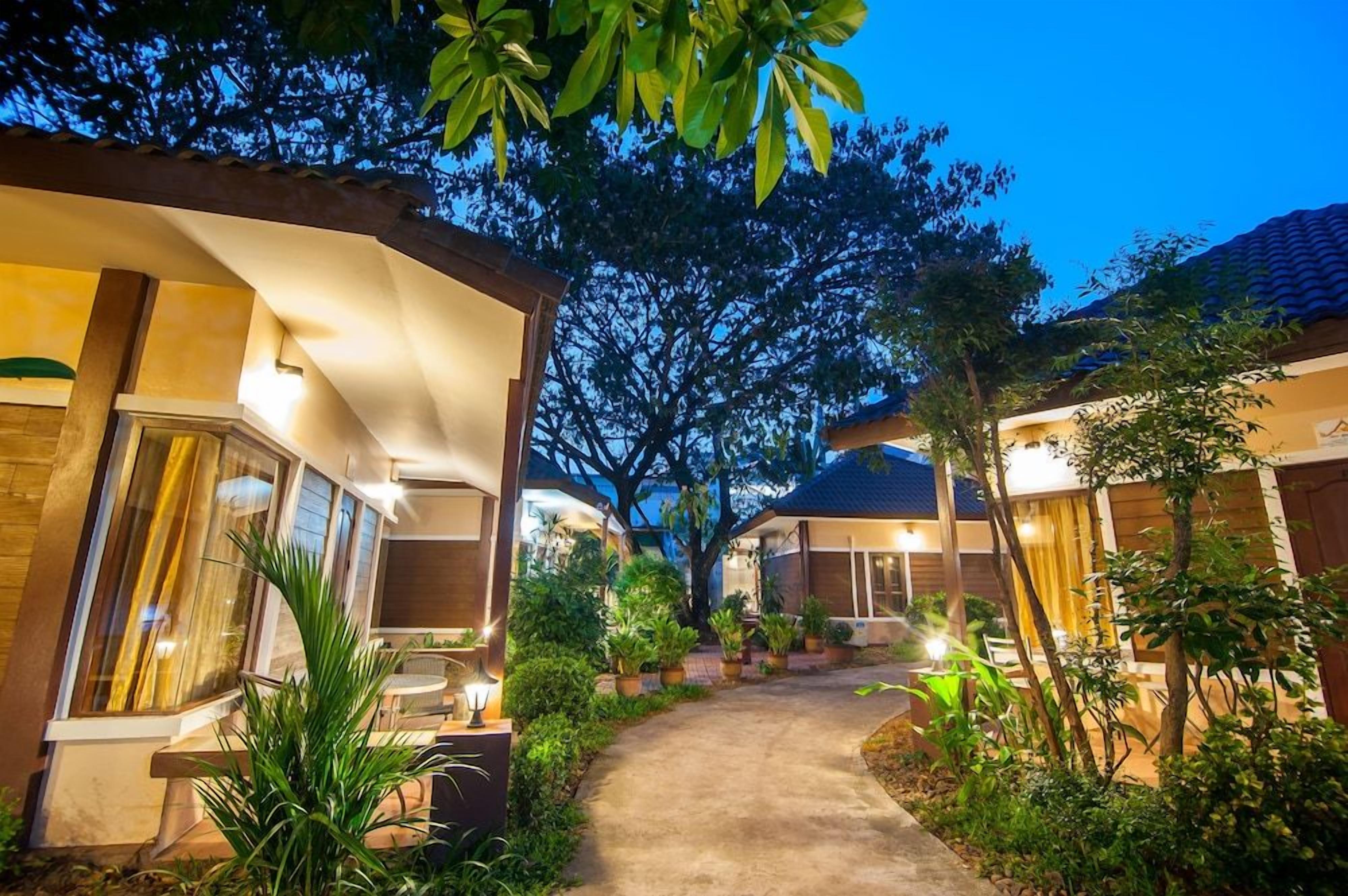 A pathway leading to a building with a covered outdoor seating area and potted plants.