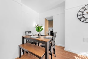 Un comedor con una mesa de madera, sillas y una planta en maceta.