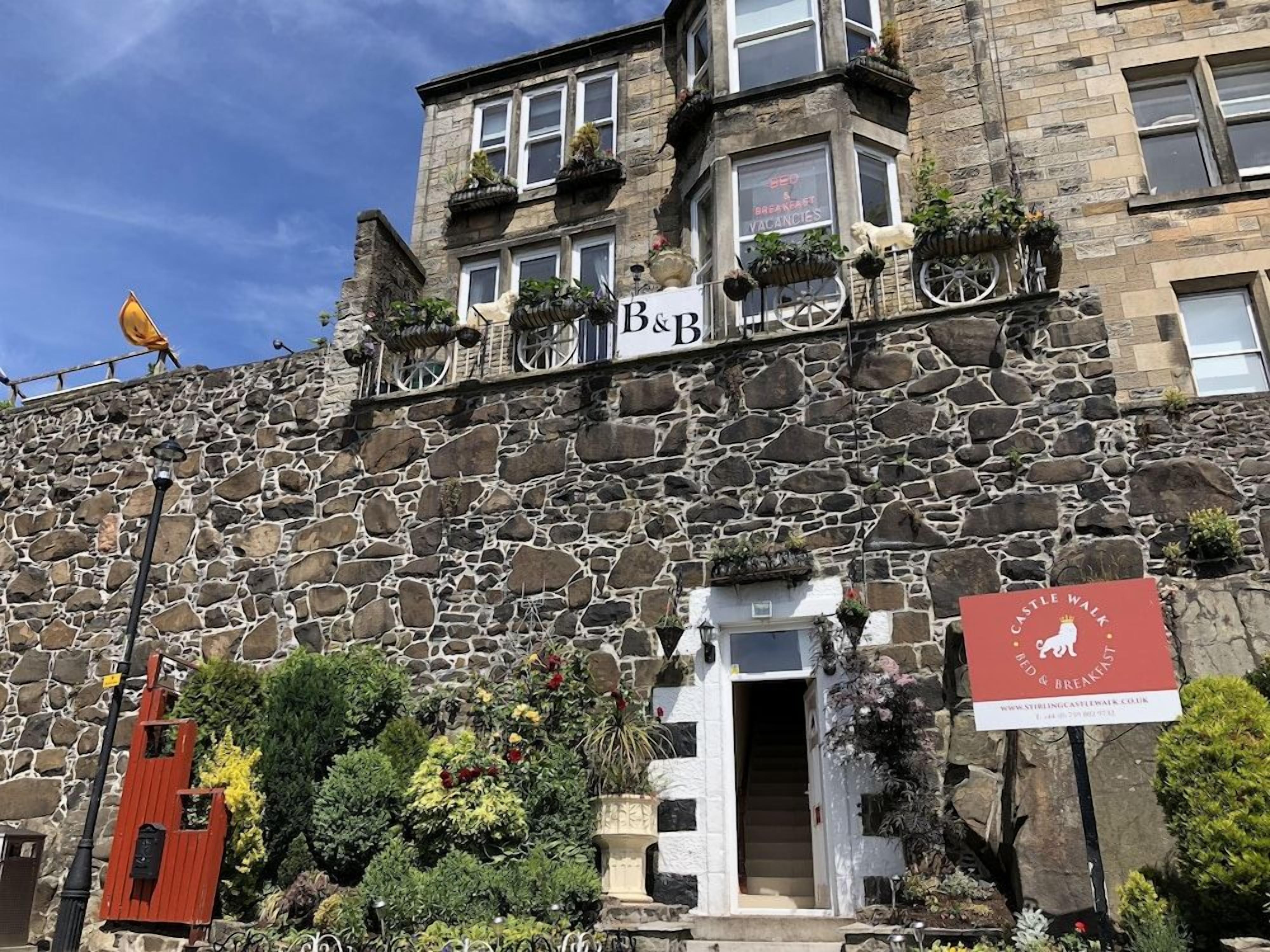 A stone building with a sign for 'B&B' and a 'Castle Walk' sign.