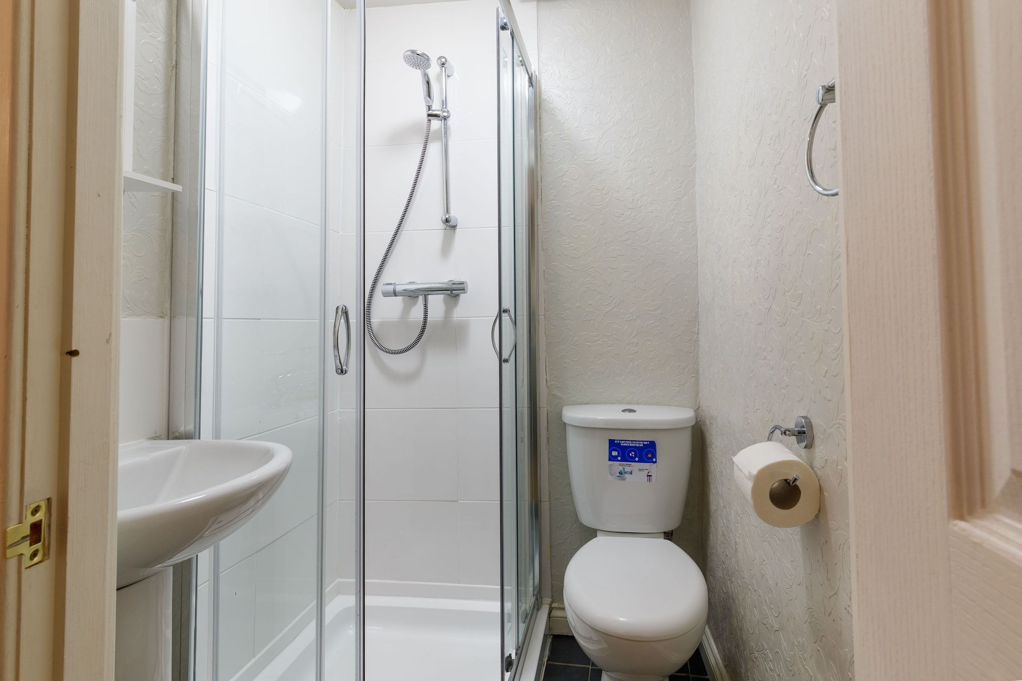 A small bathroom with a glass-enclosed shower, a white toilet, and a sink.
