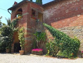 Un edificio rústico con fachada de ladrillo, pared de piedra y una pequeña entrada en arco.