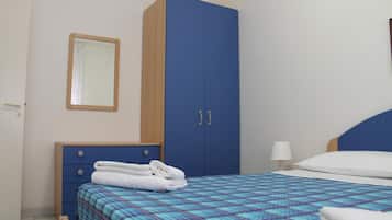 Ein Schlafzimmer mit einem Bett, einem Kleiderschrank, einem Spiegel und einem Nachttisch.