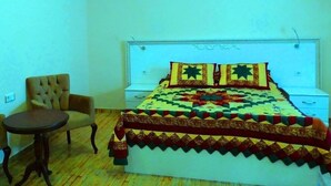 Un dormitorio con una cama, dos sillones y una pequeña mesa redonda.