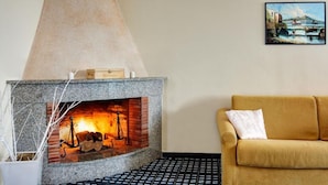 Una chimenea con repisa de piedra, un sofá con cojín y un cuadro en la pared.