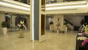 A spacious lobby with a glass coffee table, seating area, and a staircase. - Triple Tree Hotel (Al-Hofuf)