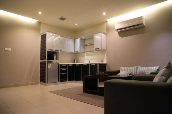 A compact living space with a kitchenette, a sofa, and a coffee table.