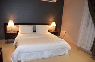 A hotel room with a bed, two bedside lamps, a nightstand, and a curtain.