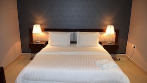 A neatly made bed with white linens, two bedside lamps, and a power outlet on the nightstand. - Triple Tree Hotel (Al-Hofuf)