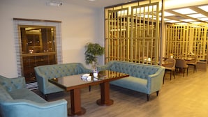 A room with a sofa, chairs, a table, and a decorative partition. - Triple Tree Hotel (Al-Hofuf)