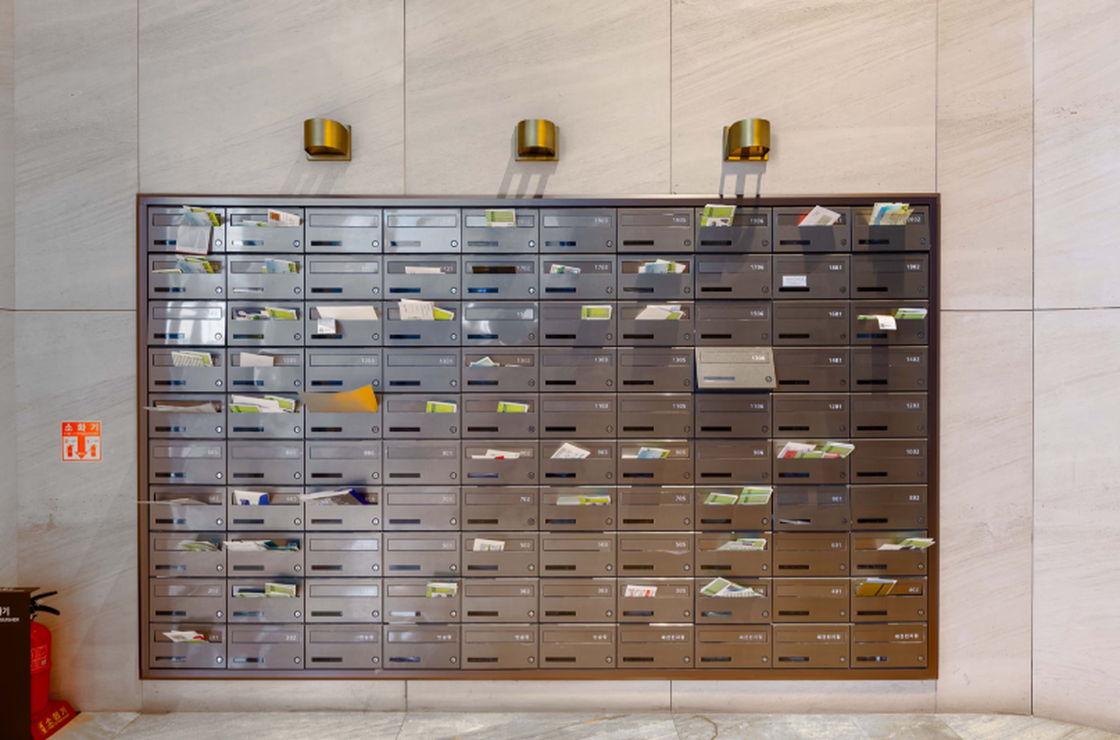A wall of mailboxes with labels, a fire extinguisher, and a fire exit sign.