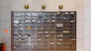 A wall of mailboxes with labels, a fire extinguisher, and a fire exit sign.