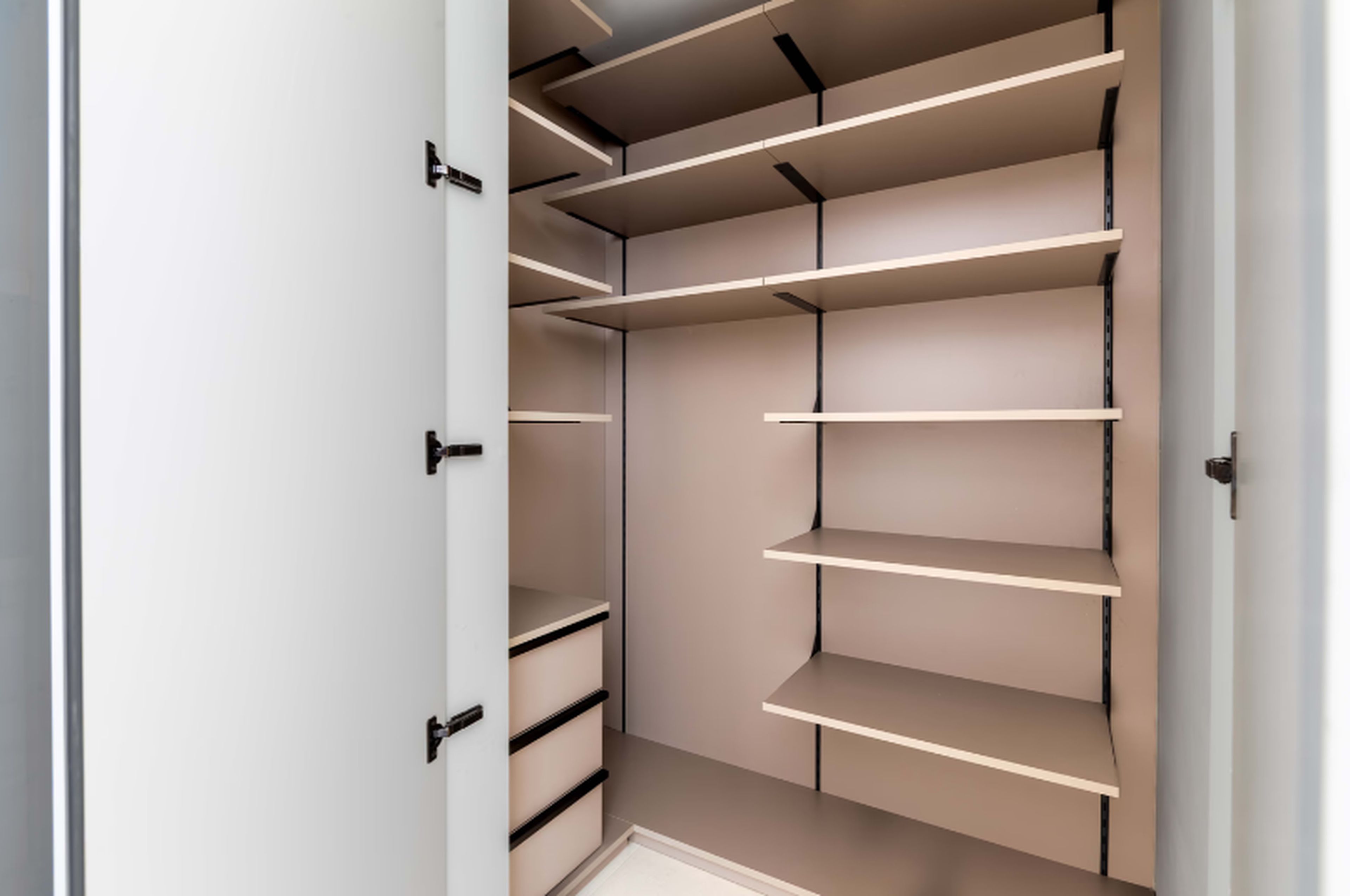 A walk-in closet with multiple shelves and drawers.