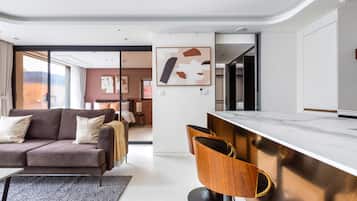 A modern living room with a sofa, a coffee table, and a dining area with a bar.