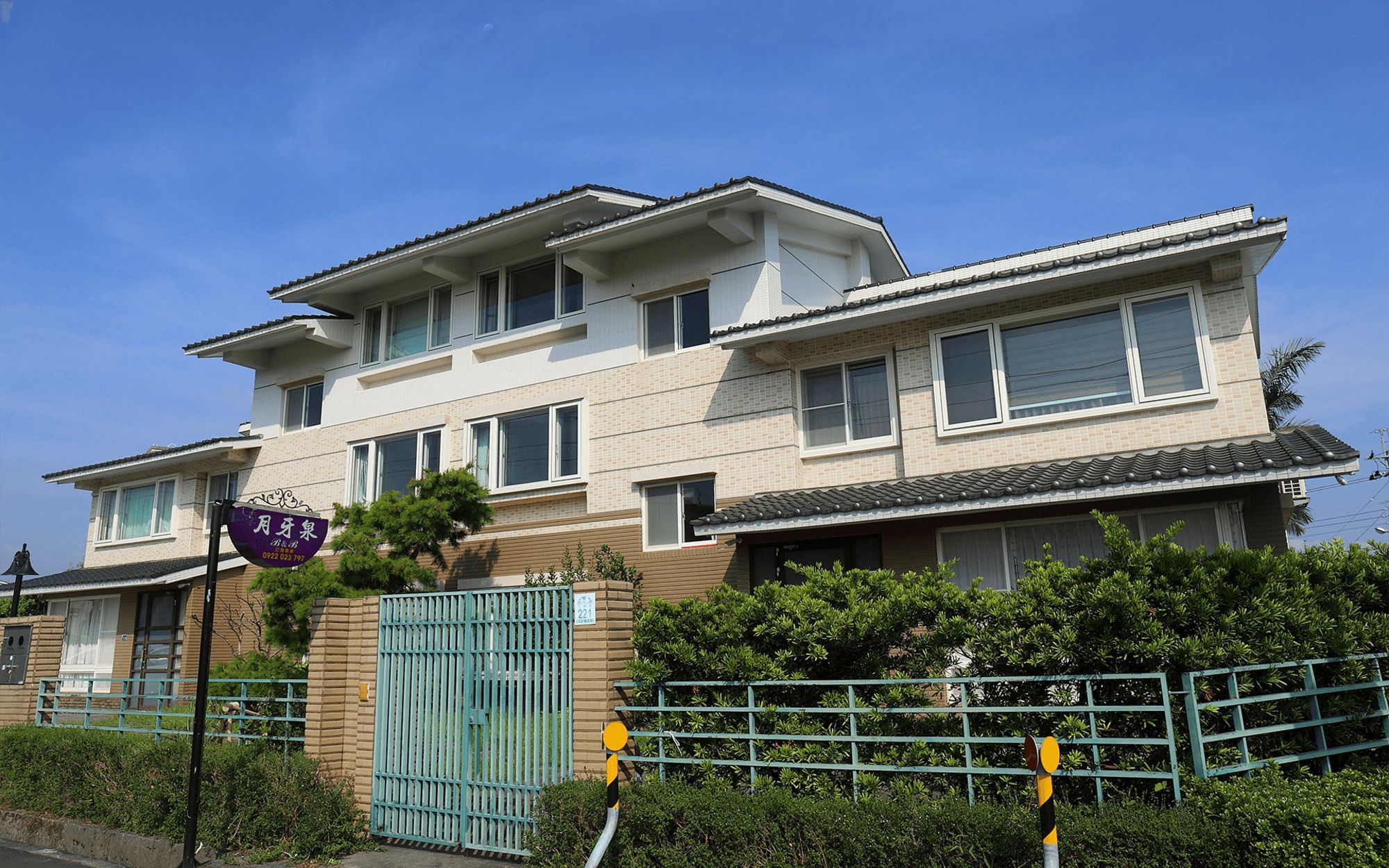 A multi-story residential building with a gated entrance, a visible mailbox, and a clear sky.