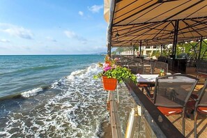 A seaside restaurant with outdoor seating overlooking the ocean, featuring a covered patio and a view of the waves. - Regina Maria Spa Design Hotel (Balchik)