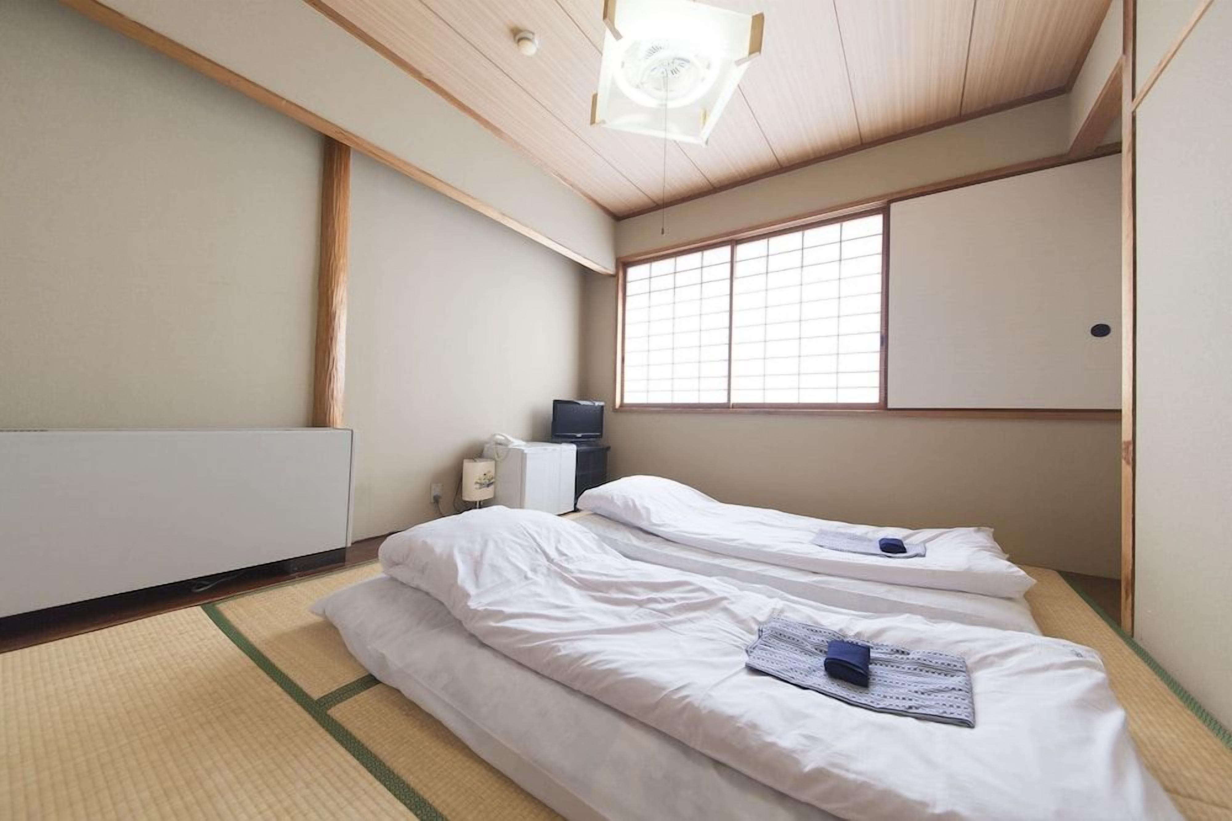 A room with two beds, a radiator, a television, and a large window.