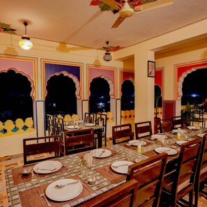 A dining area with tables set for four, chairs, and a ceiling fan. - Treebo Rajputana Ranthambore (Sawai Madhopur)