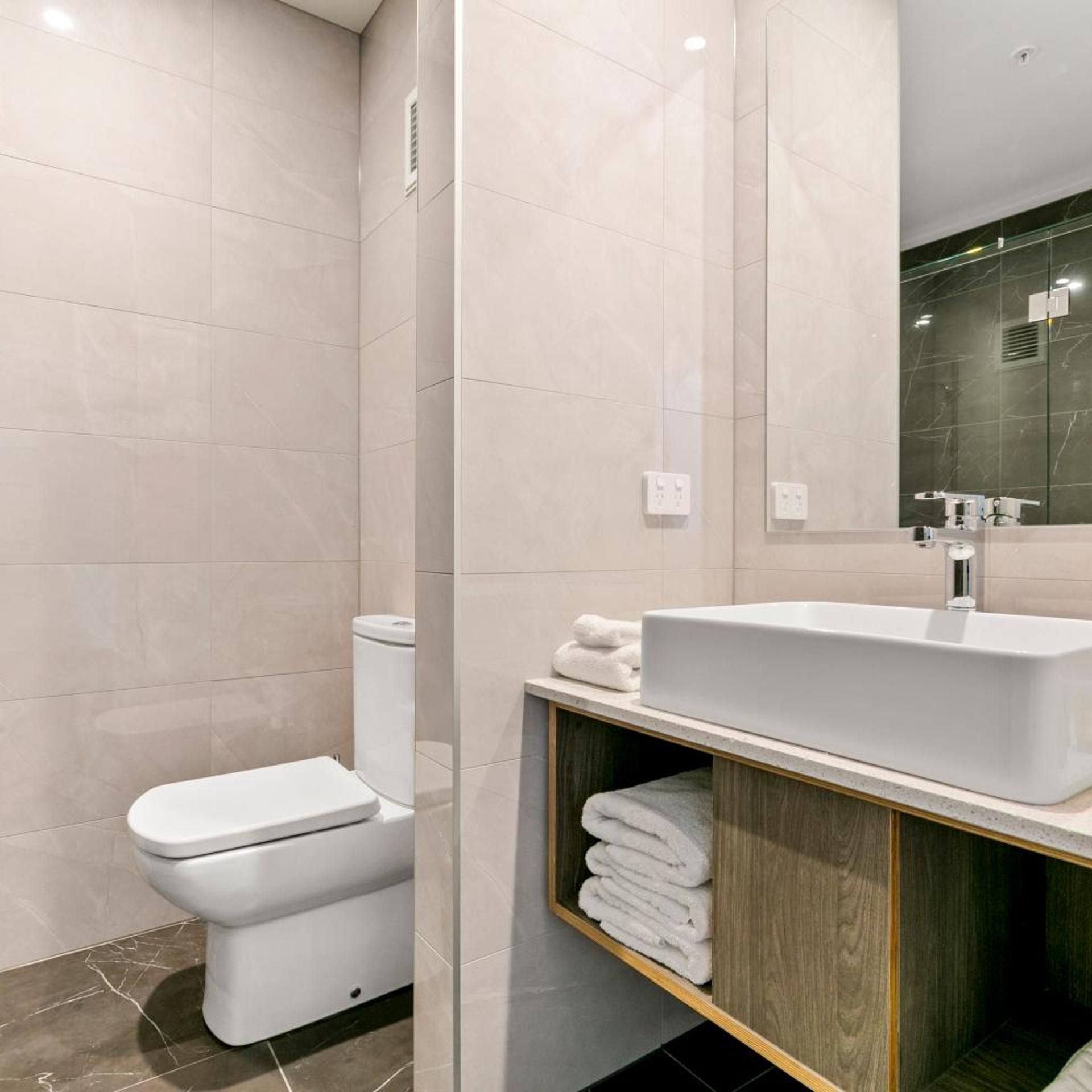 A modern bathroom with a toilet, sink, and mirror.