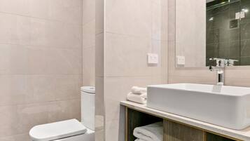 A modern bathroom with a toilet, sink, and mirror.