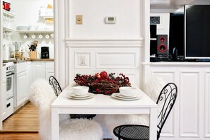 A white dining table with a decorative centerpiece, white cabinetry, and a black kitchen area with a microwave and red speakers. - Unique style condo with HOT TUB! (Denver)