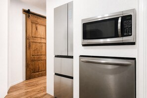 A kitchen with a microwave, a refrigerator, and a wooden door. - Unique style condo with HOT TUB! (Denver)