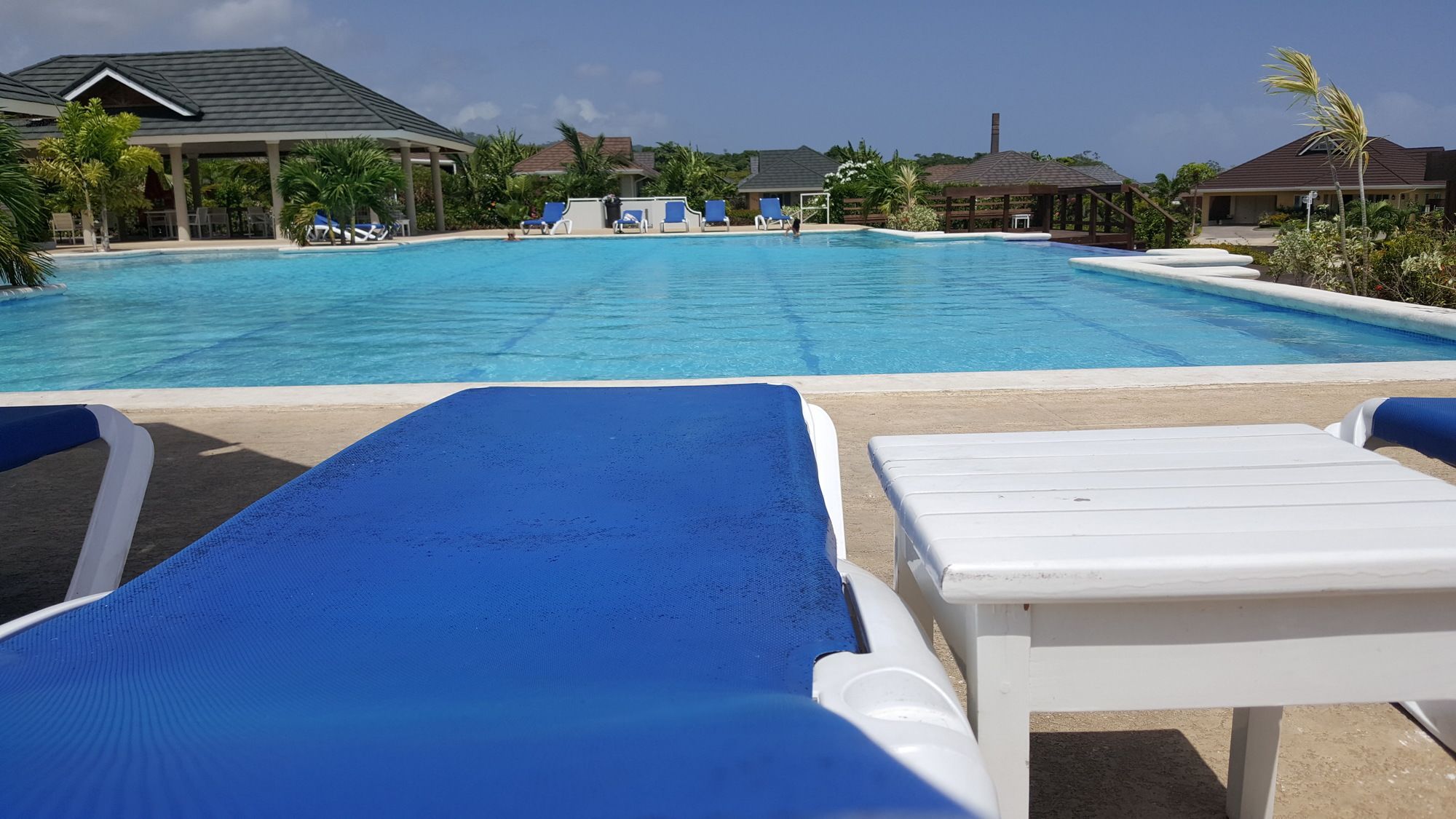 Piscina com espreguiçadeiras e área coberta.
