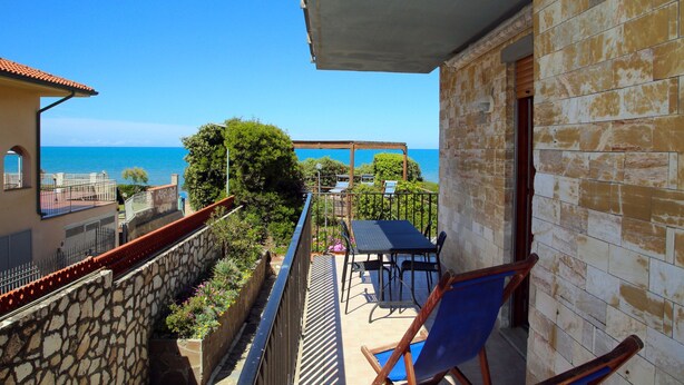 Varanda com vista para o mar, pérgola e área de estar ao ar livre.