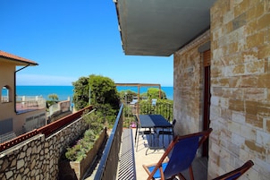 A balcony with a view of the sea, a pergola, and outdoor seating.