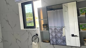 A bathroom with a white sink, a mirror, a towel rack, and a window with a view of greenery outside. - R&R Rest & Restore (Bogwalk)