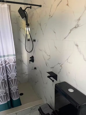 Uma casa de banho com chuveiro, sanita e lavatório.