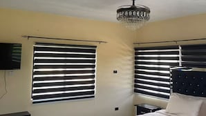 A bedroom with a bed, a chandelier, and two windows with blinds. - R&R Rest & Restore (Bogwalk)