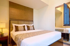 Una habitación de hotel con una cama grande, una mesita de noche con lámpara y un espejo sobre la cama.