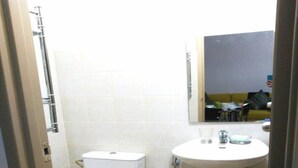 A small bathroom with a toilet, sink, and mirror.