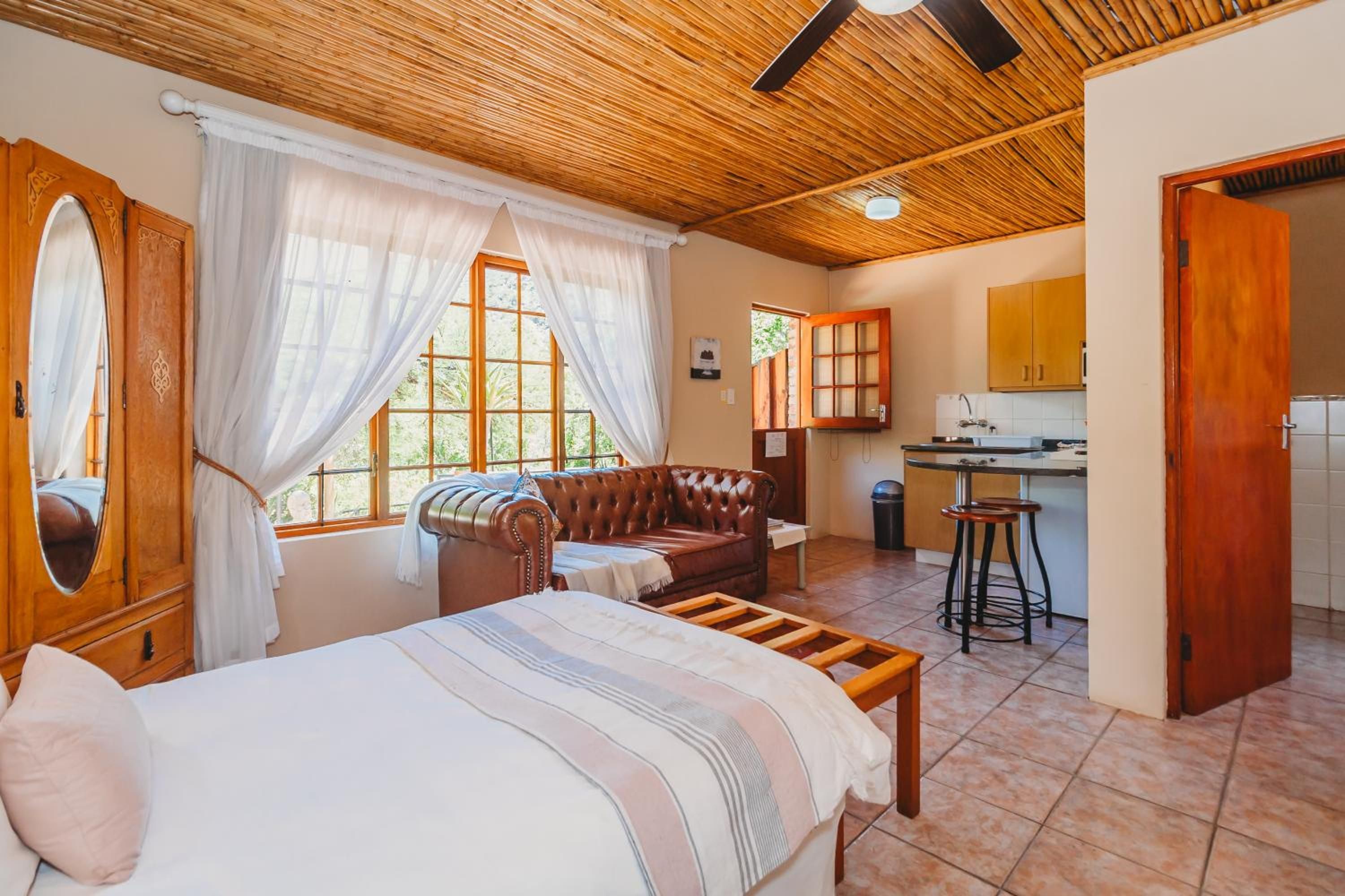 A room with a bed, a sofa, a dining area, and a kitchen.