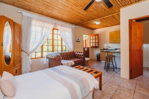 A room with a bed, a sofa, a dining area, and a kitchen.