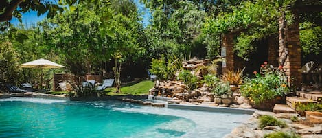 A swimming pool surrounded by lush greenery and a brick structure.