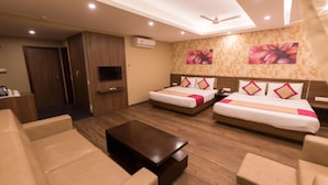 A hotel room with two beds, a sofa, a coffee table, a TV, and a ceiling fan. - Le Roi (Kanthi)
