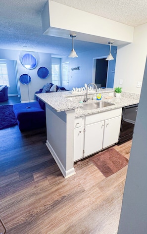 A modern kitchen with white cabinetry, granite countertops, and a built-in dishwasher.