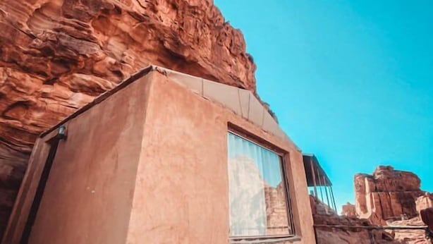 A modern building with a large window, situated in a rocky landscape. - Martian 2 (Wadi Rum)