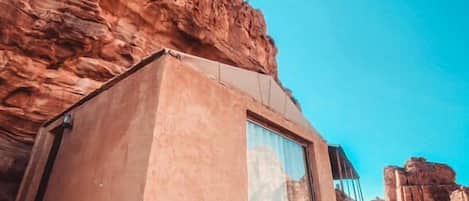 A modern building with a large window, situated in a rocky landscape.