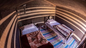 A tent with two beds, a small table, and a chair. - Martian 2 (Wadi Rum)