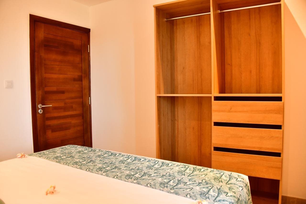 Un dormitorio con un armario de madera, una cama con colcha estampada y una puerta.