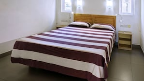 Habitació individual amb un llit de veta, dues taules de nit i un edredó rayat.